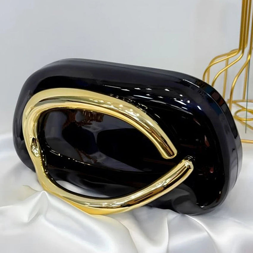Black and gold clutch bag on a white satin cloth.