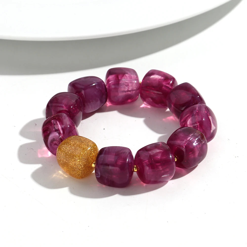 Purple beaded bracelet with a gold bead on a white background
