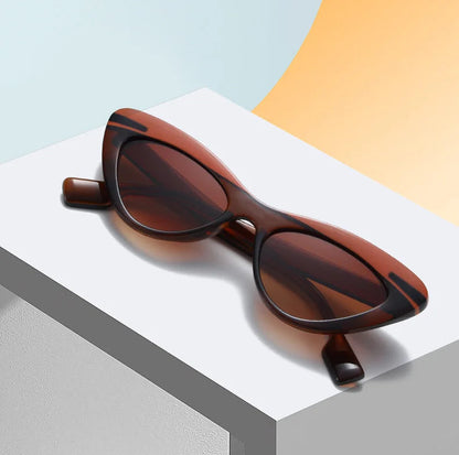 Brown sunglasses on a white surface with a multicolor background