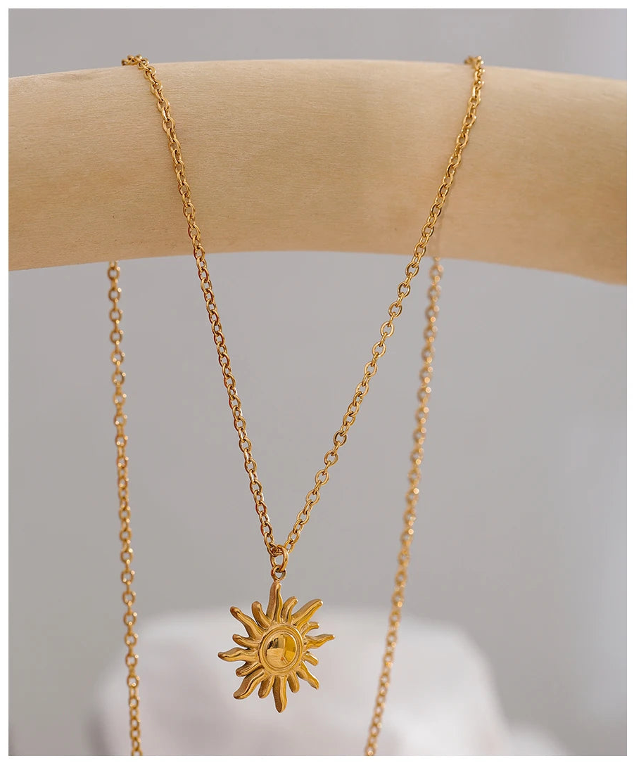 Gold necklace with a sun pendant on a neutral background