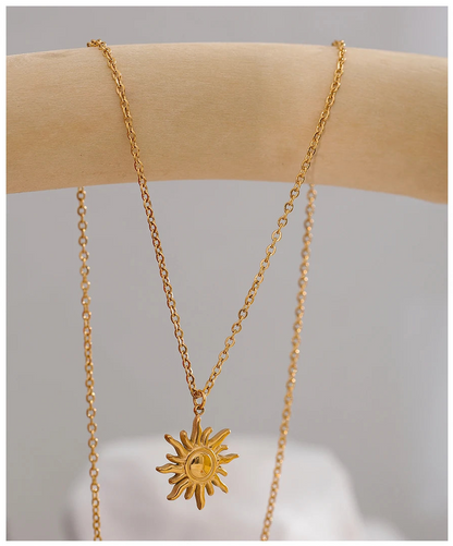 Gold necklace with a sun pendant on a neutral background