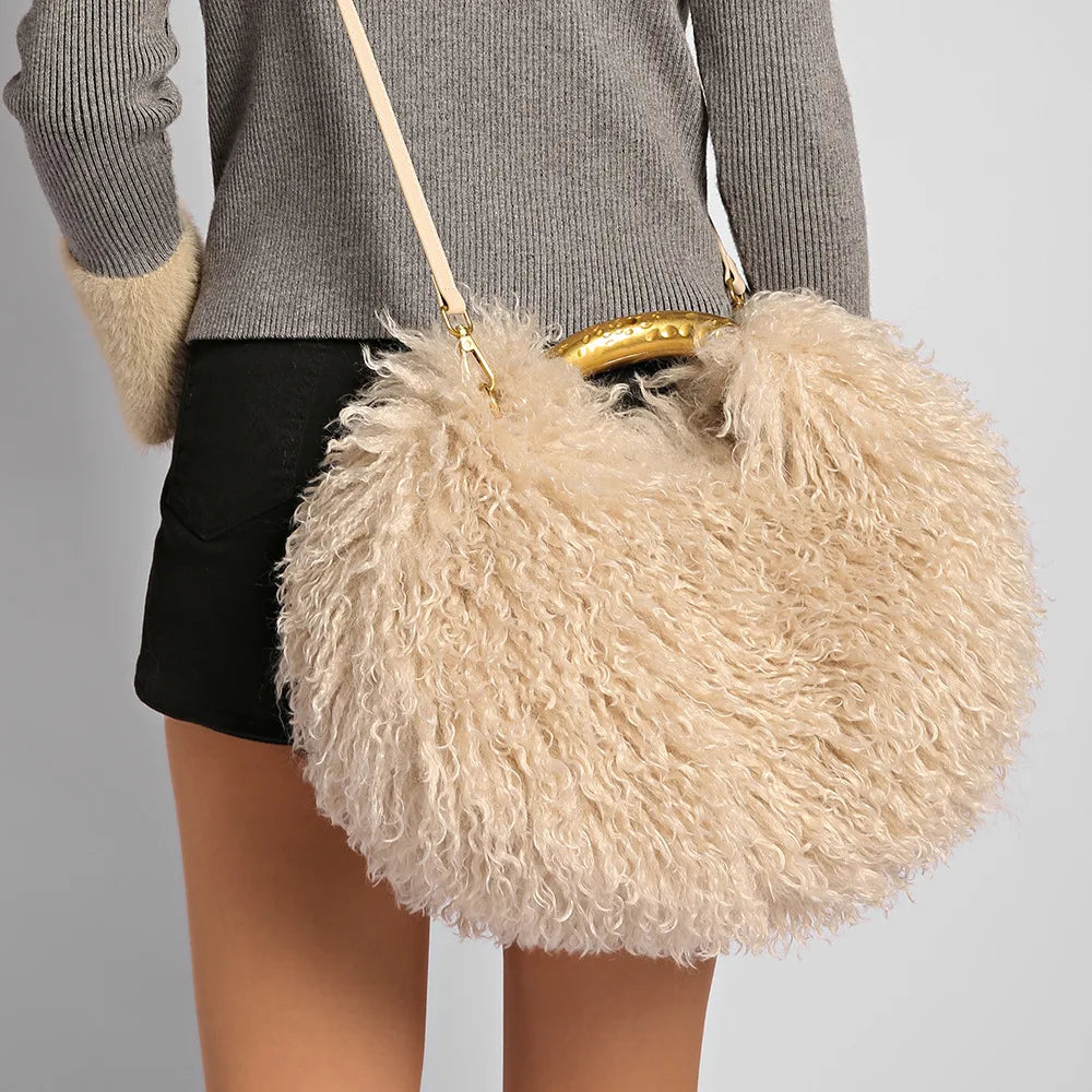 Beige fluffy handbag with gold handle held by a person wearing a grey sweater and black shorts.