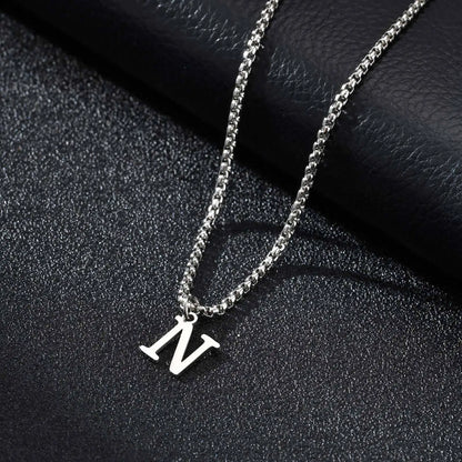Silver necklace with a 'N' pendant on a black textured surface