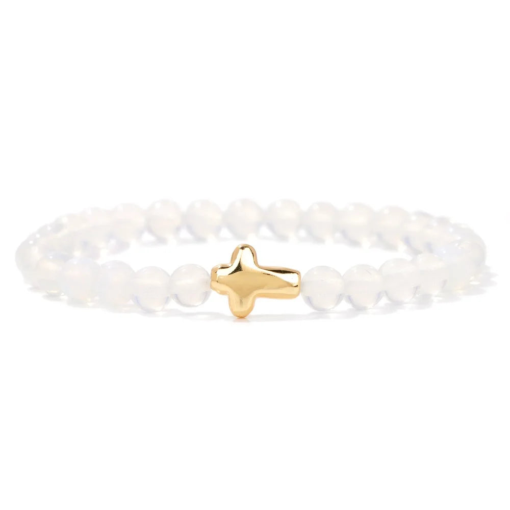White beaded bracelet with a gold cross charm on a white background