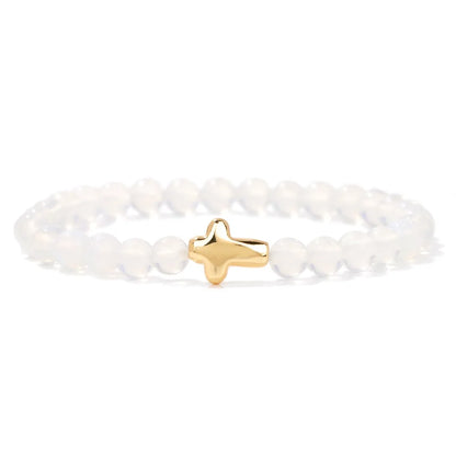 White beaded bracelet with a gold cross charm on a white background