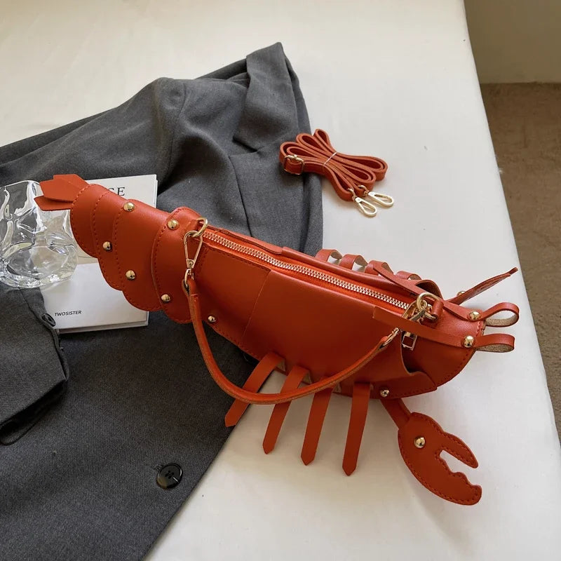 Brown lobster-shaped handbag on a white surface with a grey garment and clear glass in the background.