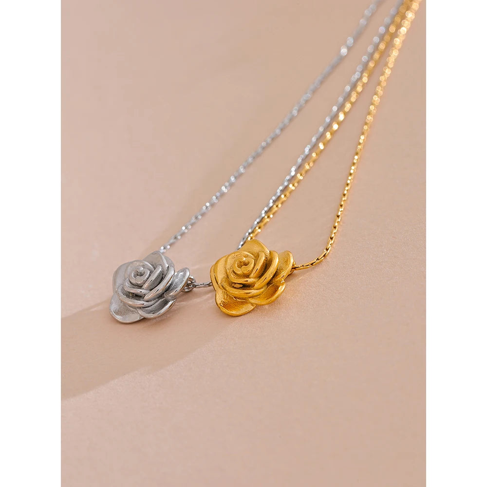 Two rose-shaped pendants on gold and silver chains against a beige background