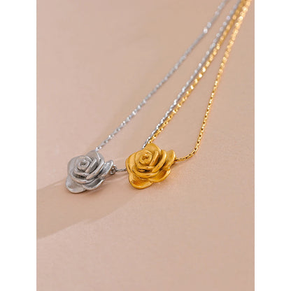Two rose-shaped pendants on gold and silver chains against a beige background