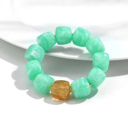 Green beaded bracelet with a gold accent on a white background