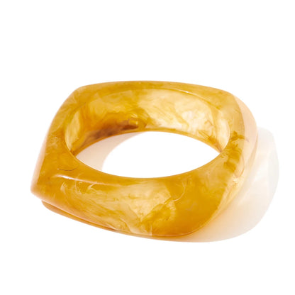 Yellow bangle with a geometric design on a white background