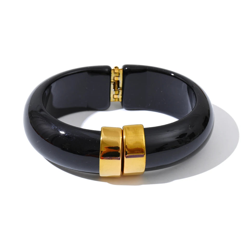 Black bracelet with gold clasp on a white background