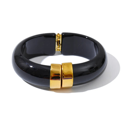 Black bracelet with gold clasp on a white background