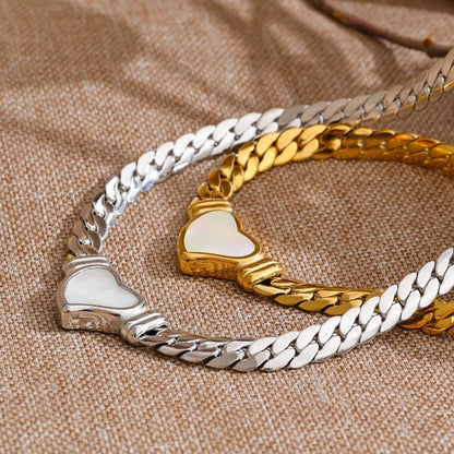 Two necklaces in gold and silver, and a heart-shaped charm on a textured brown surface.