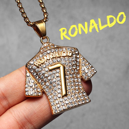 Gold necklace pendant shaped like a sports jersey with 'RONALDO' and number '7', held by a hand against a grey background.