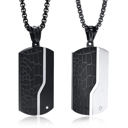 Two black and silver patterned pendants on black chains against a white background