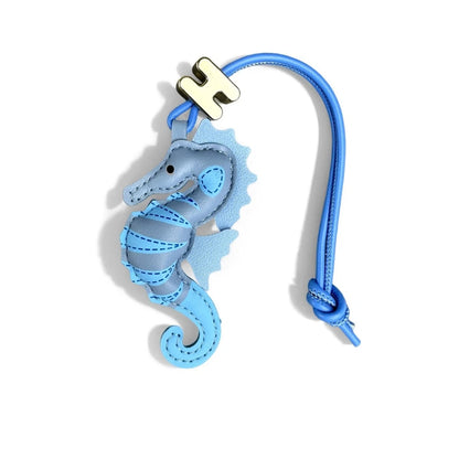 A light blue leather seahorse charm with a blue strap and a gold-tone H logo, shown on a clean white background.