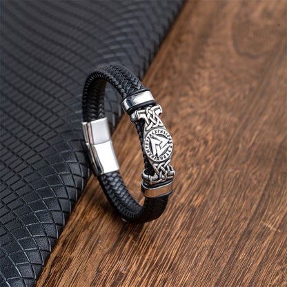 Black braided leather bracelet with silver clasp on a wooden surface