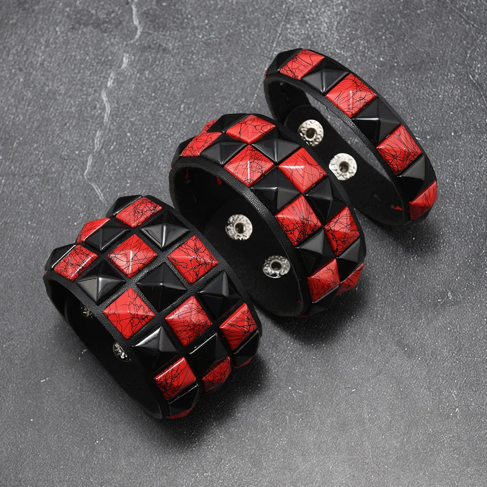 Three black and red studded bracelets on a grey surface