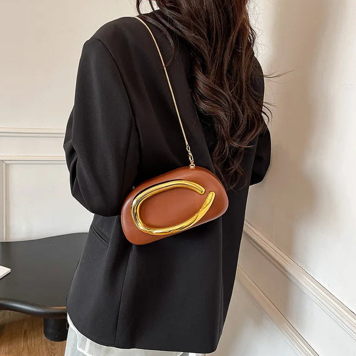 Person wearing a black outfit with a brown handbag featuring a gold clasp.