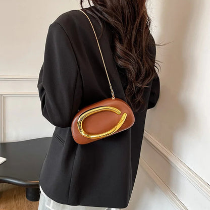 Person wearing a black outfit with a brown handbag featuring a gold clasp.