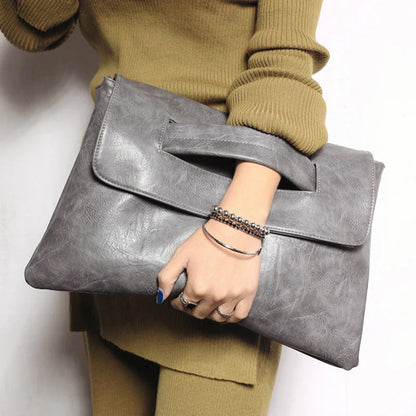 Person holding a grey clutch bag against a white background