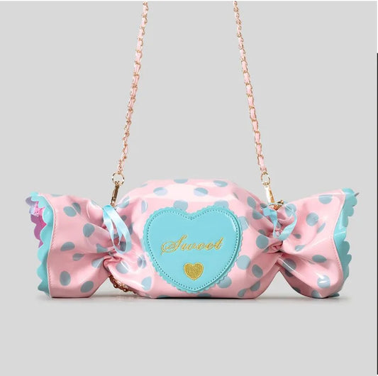 Pink polka dot bag with a large bow and heart-shaped patch on a grey background