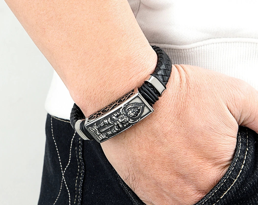 Black leather bracelet with silver clasp on a wrist against a neutral background