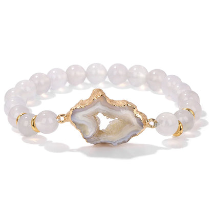 Bracelet with white beads and a gold agate slice charm on a white background