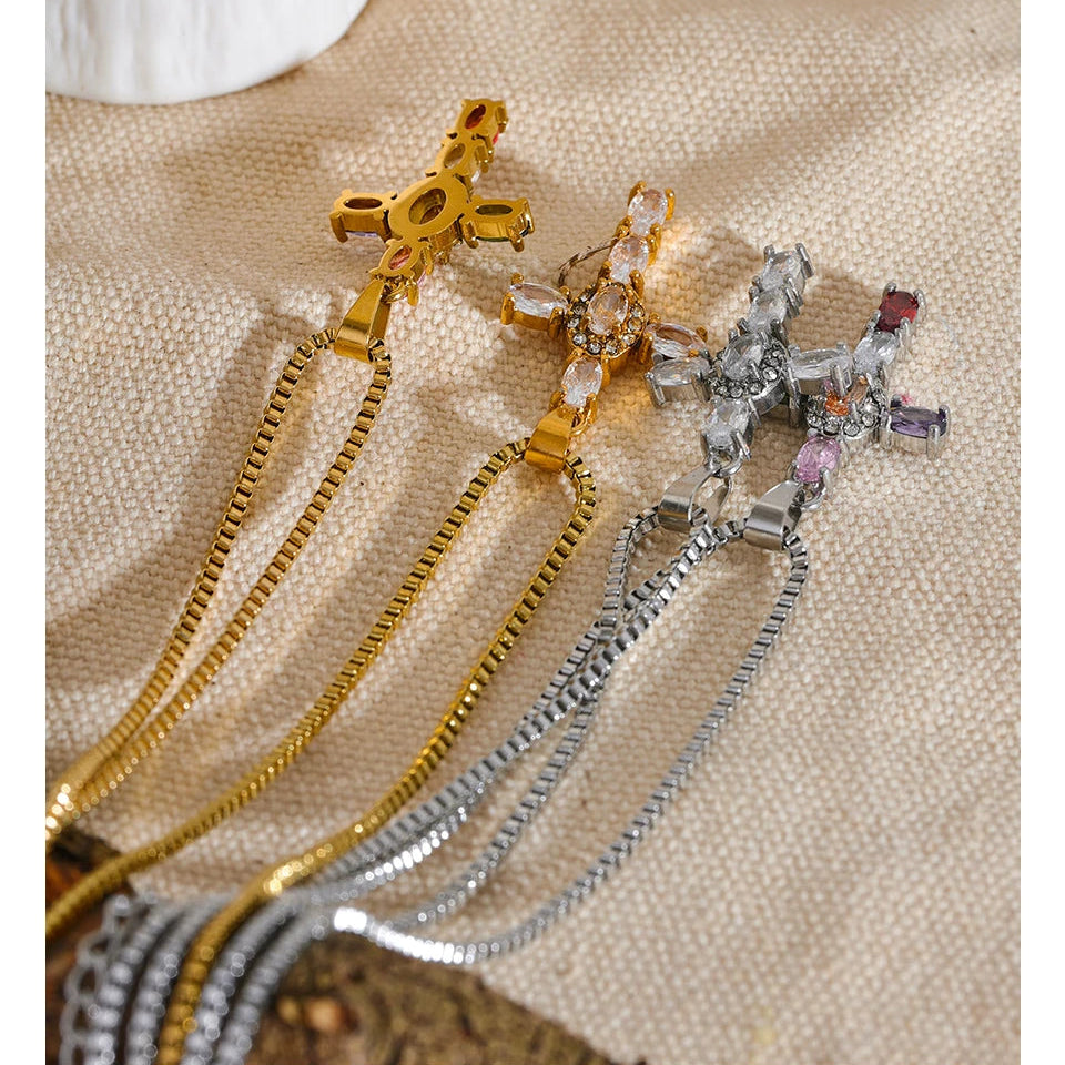 Four necklaces with cross pendants in gold and silver, on a textured surface