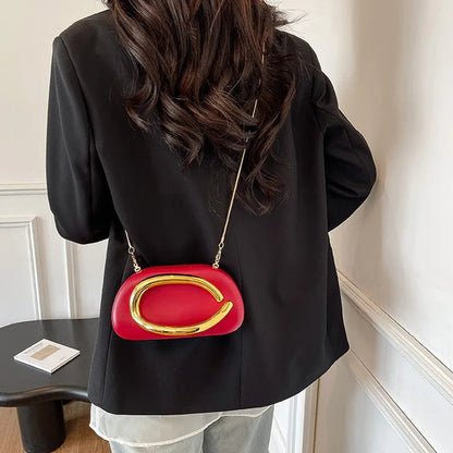 Person wearing a black jacket with a red handbag featuring a gold clasp.