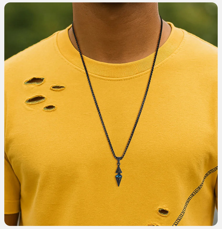 Person wearing a yellow distressed shirt with a black necklace featuring a blue pendant.