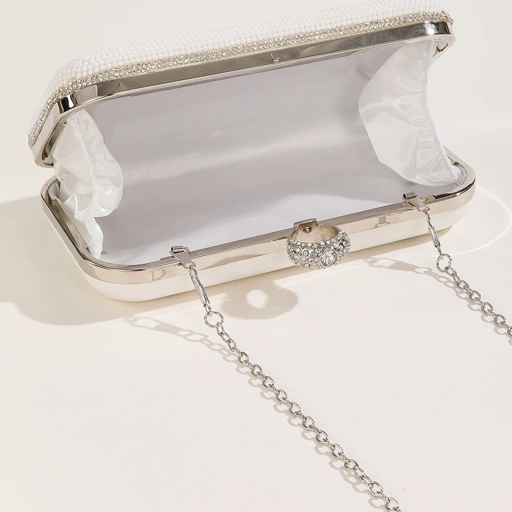 White clutch bag with silver chain on a light grey background