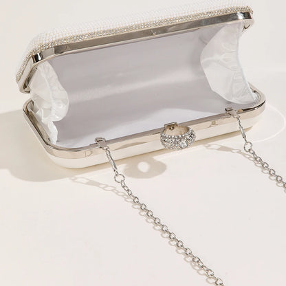 White clutch bag with silver chain on a light grey background