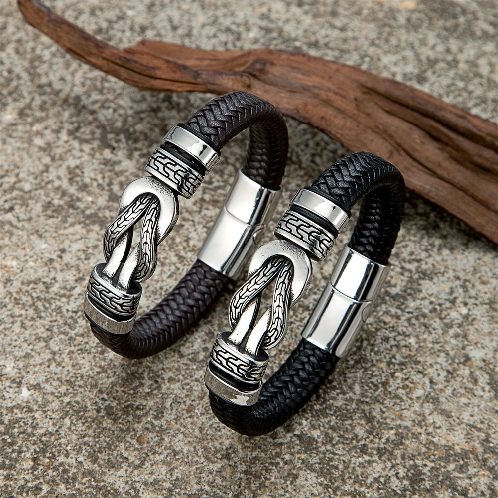 Two silver and black braided bracelets on a textured surface