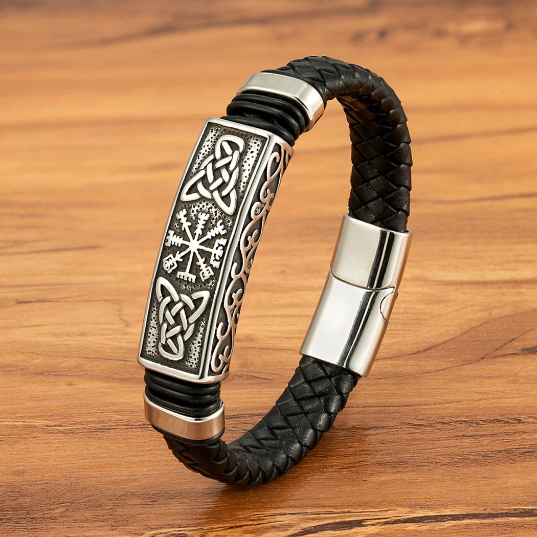 Black braided leather bracelet with silver Celtic knot design on a wooden surface