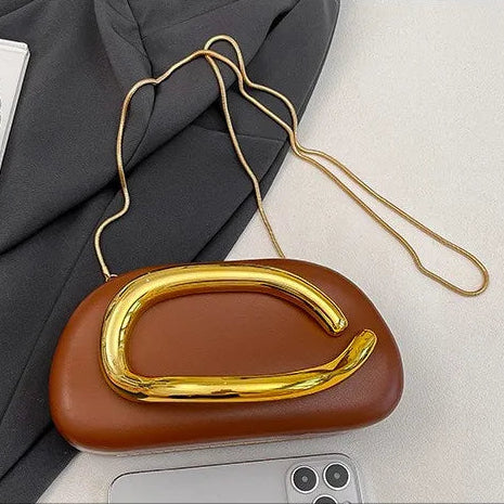 Brown clutch with gold handle on a surface