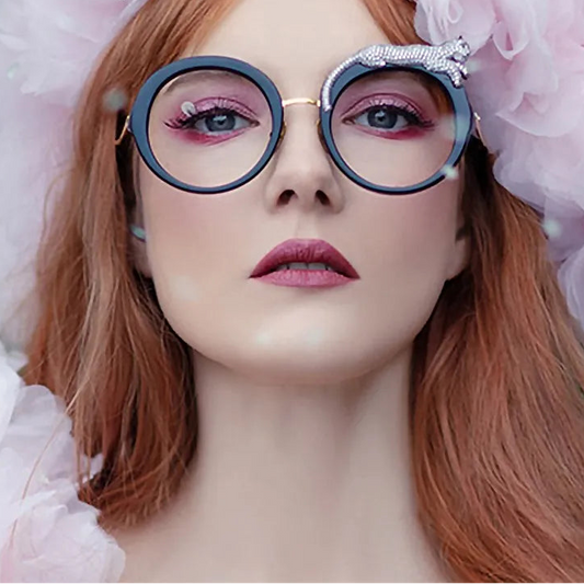 Person wearing large round glasses with decorative elements, surrounded by pink ruffled fabric.