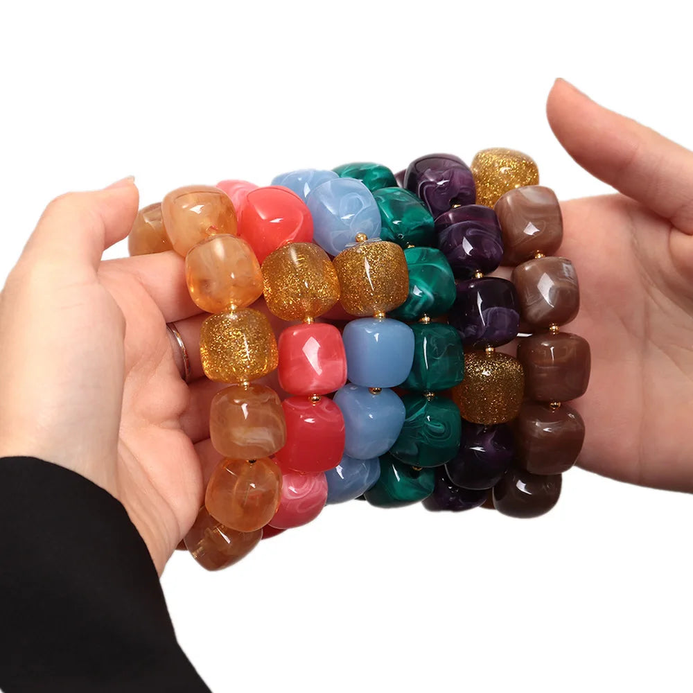 Colourful beaded bracelets held by two hands on a white background