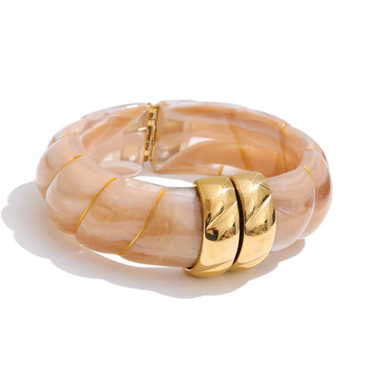 Beige bangle with gold accents on a white background