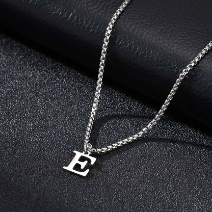Silver necklace with a 'E' pendant on a dark textured surface