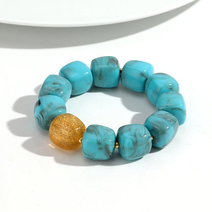 Turquoise beaded bracelet with a gold accent on a white background