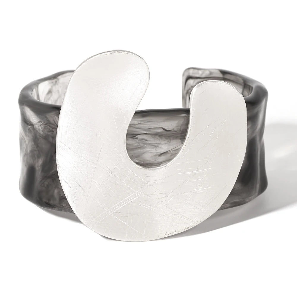 Crescent-shaped silver ring with marbled grey bangle on a white background