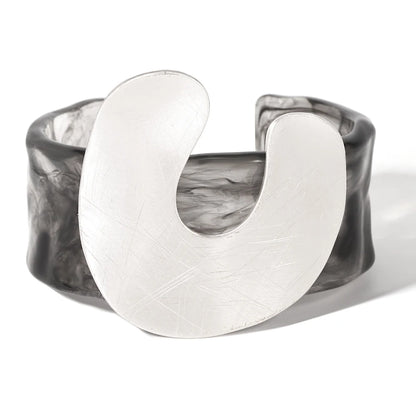 Crescent-shaped silver ring with marbled grey bangle on a white background