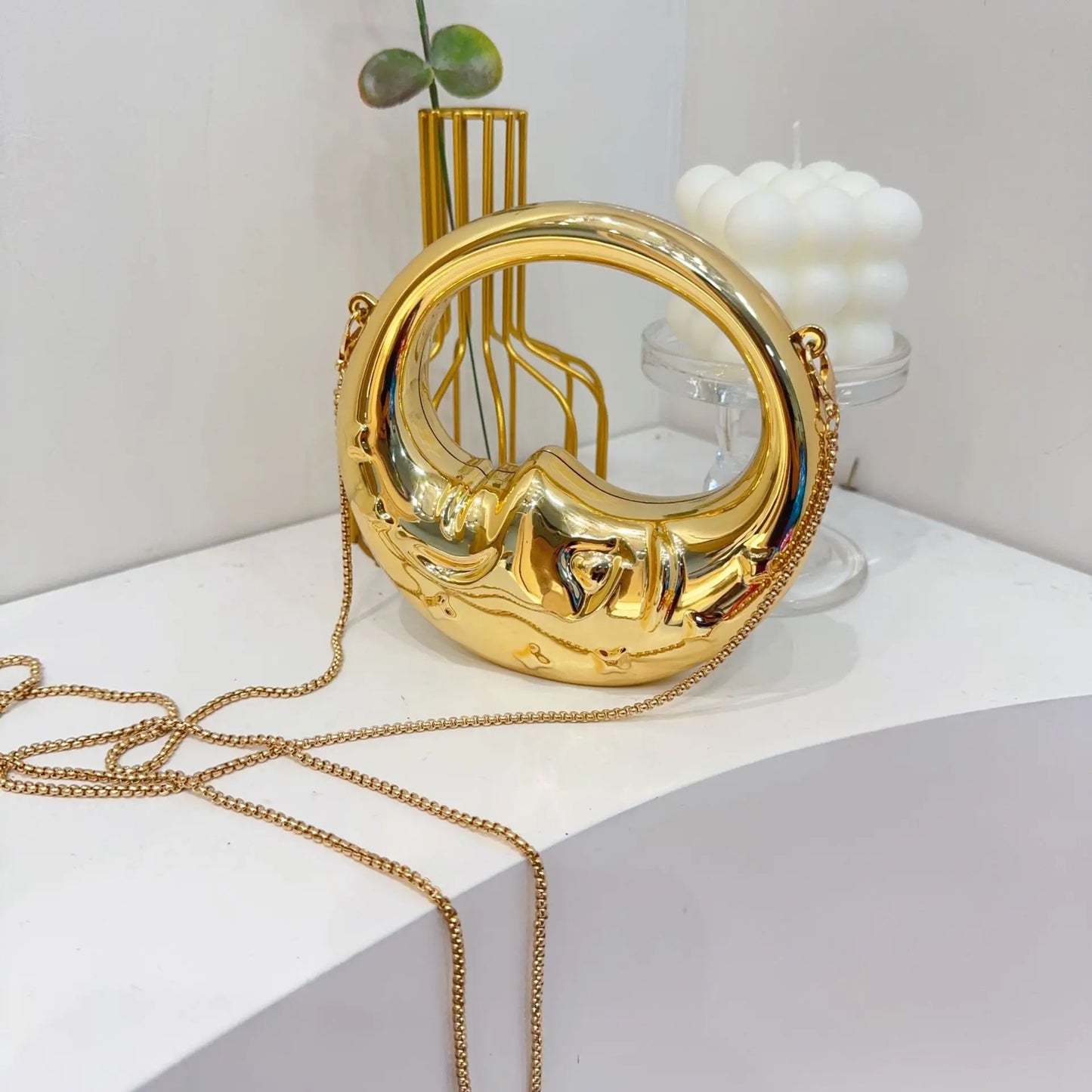 Gold crescent handbag with chain strap on a white surface