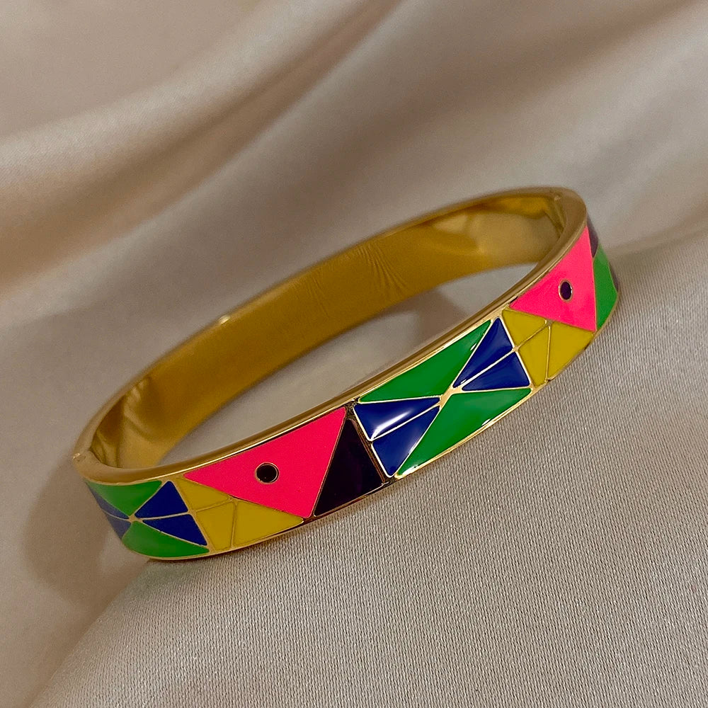 Gold bracelet with colourful geometric pattern on a beige fabric background