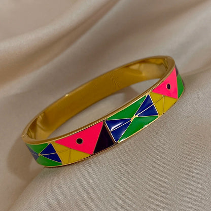 Gold bracelet with colourful geometric pattern on a beige fabric background