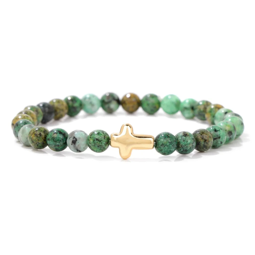 Green beaded bracelet with a gold cross charm on a white background