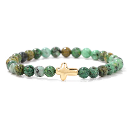 Green beaded bracelet with a gold cross charm on a white background