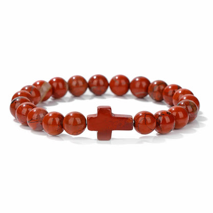Red beaded bracelet with a cross charm on a white background