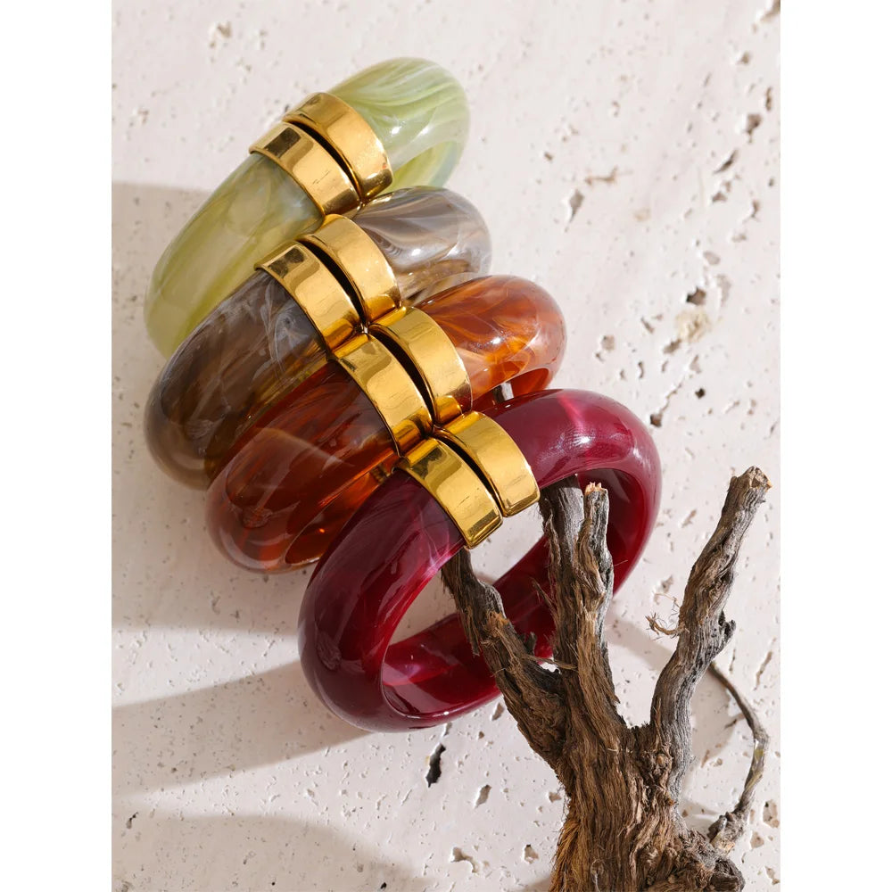 Set of colourful bangles with gold bands on a textured surface